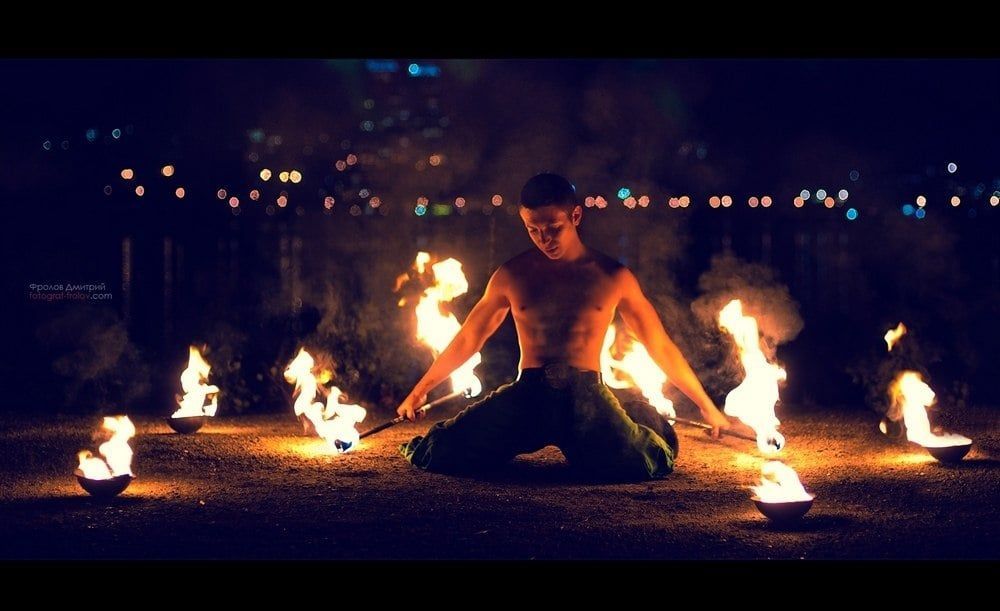 A dramatic firelit portrait: a man performs by a circle of flames during an intense photo shoot