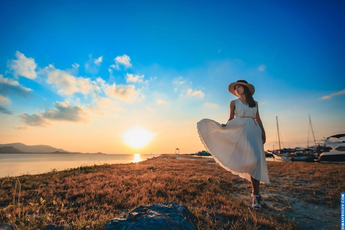 Dreamy seaside photo of a woman in white dress at golden hour