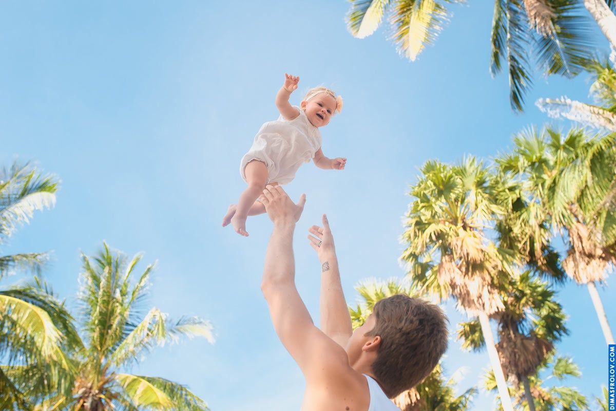 Joyful baby photo session — candid moment of flying baby with tropical sky