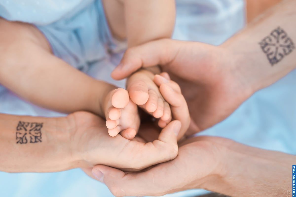 Symbolic family portrait — photo of three generations holding baby’s hand in a meaningful shot