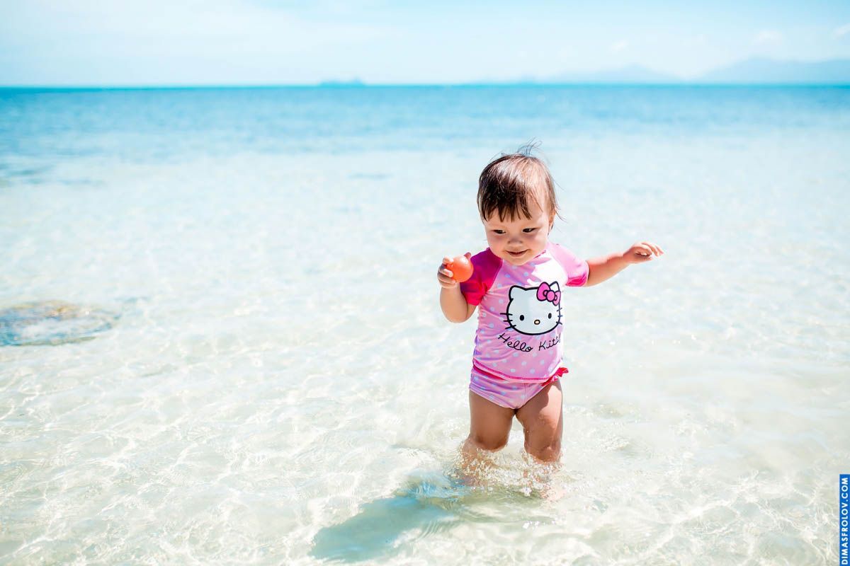 Toddler beach photo — playful moment standing in crystal clear water