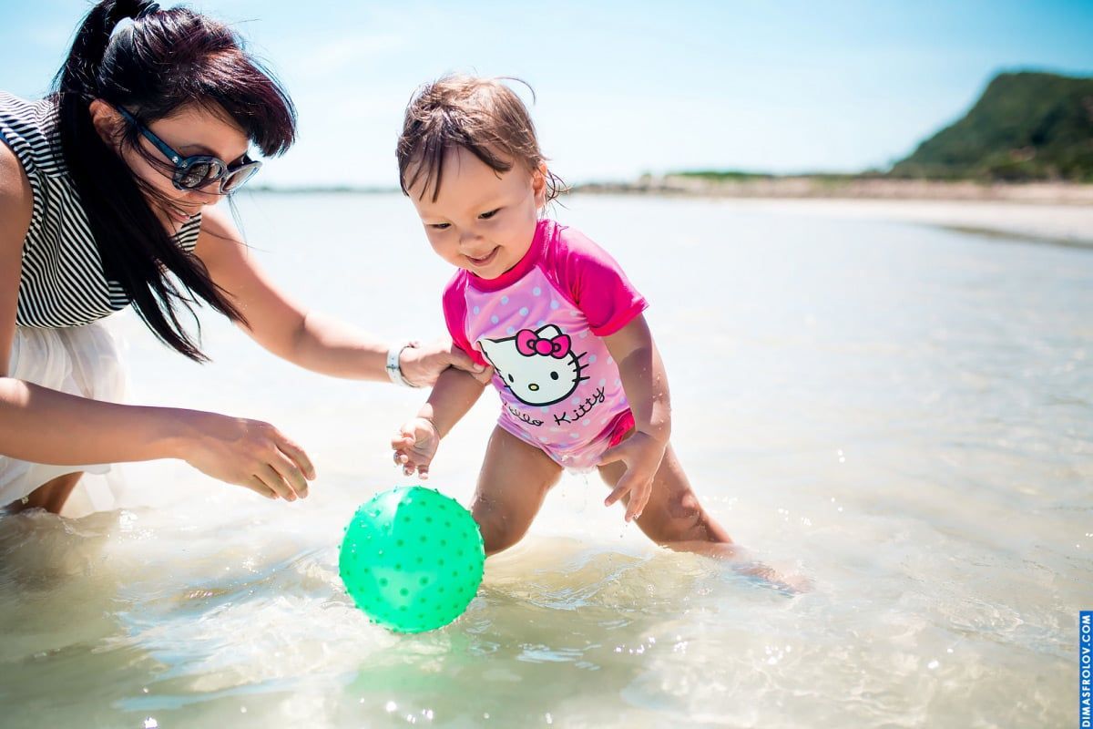 Toddler beach photo shoot — girl playing in shallow water with mom