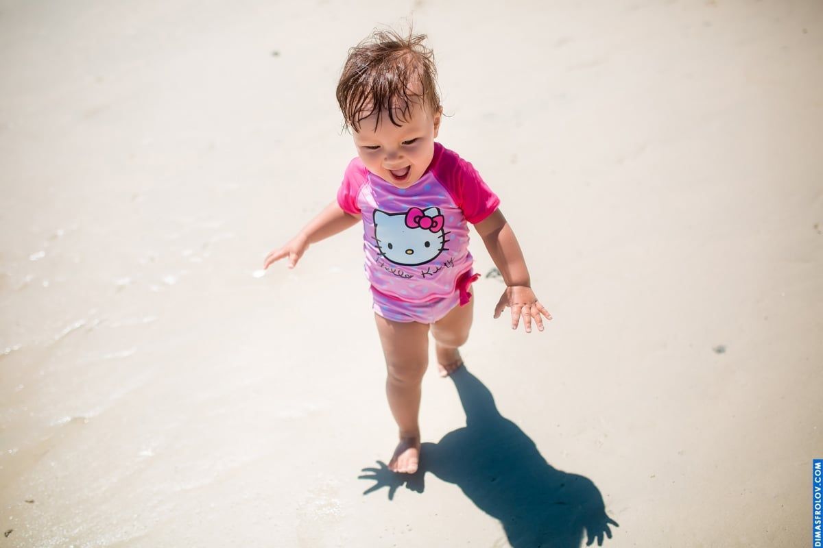 Candid beach photo — toddler in Hello Kitty swimsuit running on sand