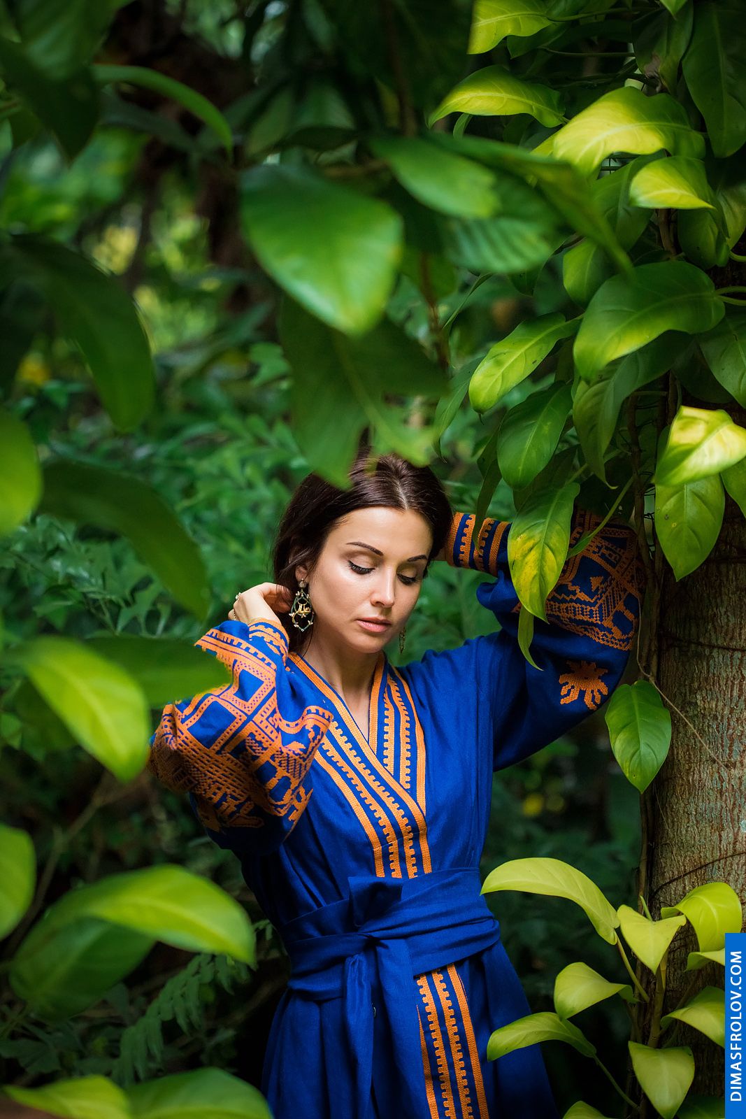 Retrato de uma mulher estilosa em um vestido étnico azul entre as folhas da selva