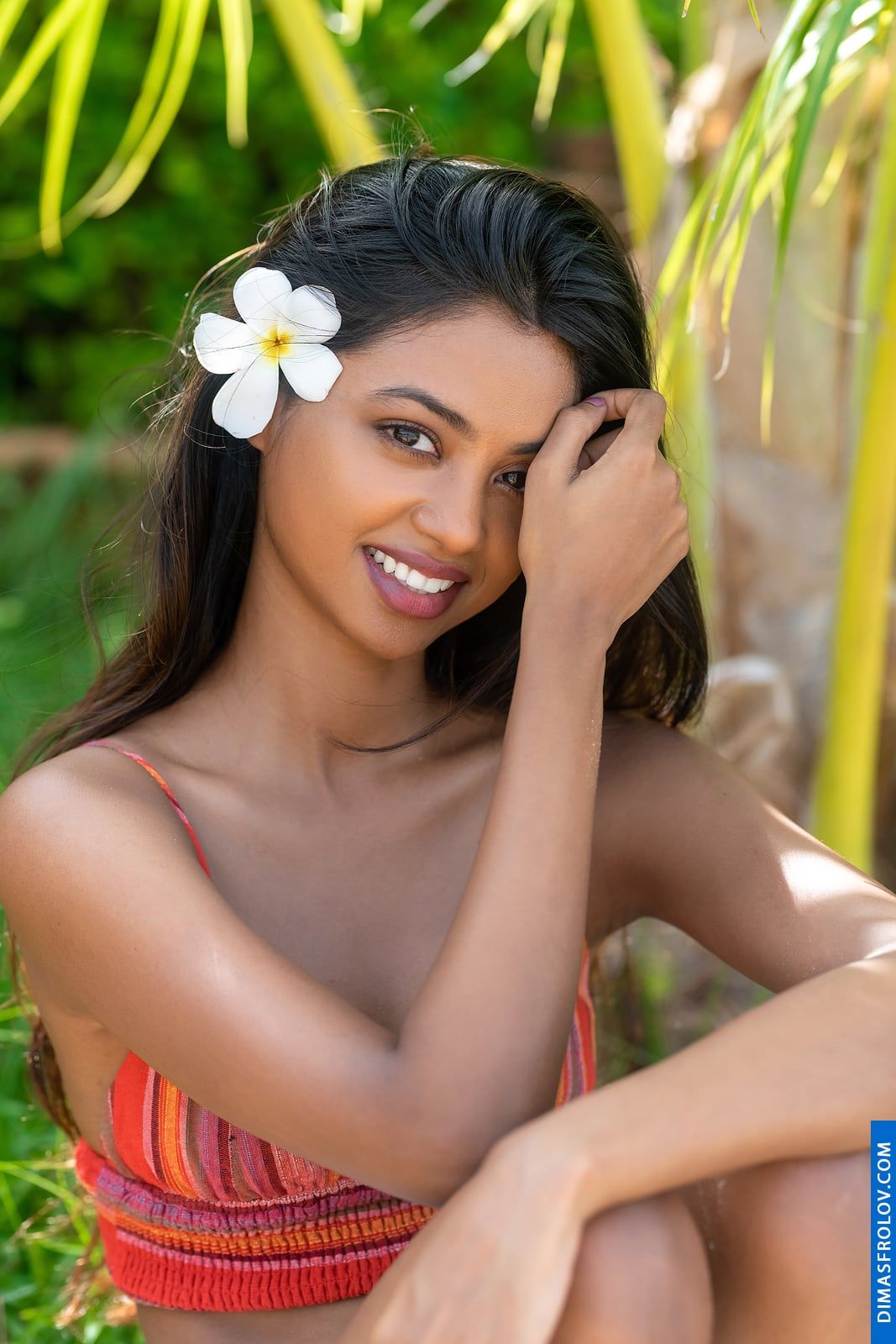 Beleza sorridente com uma flor tropical no cabelo durante uma sessão de retrato
