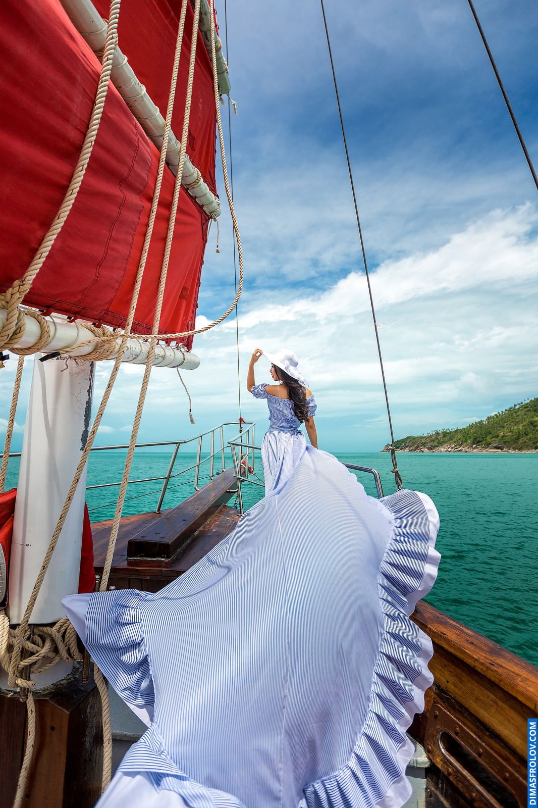 Dama em um longo vestido esvoaçante durante uma elegante sessão de fotos em um barco