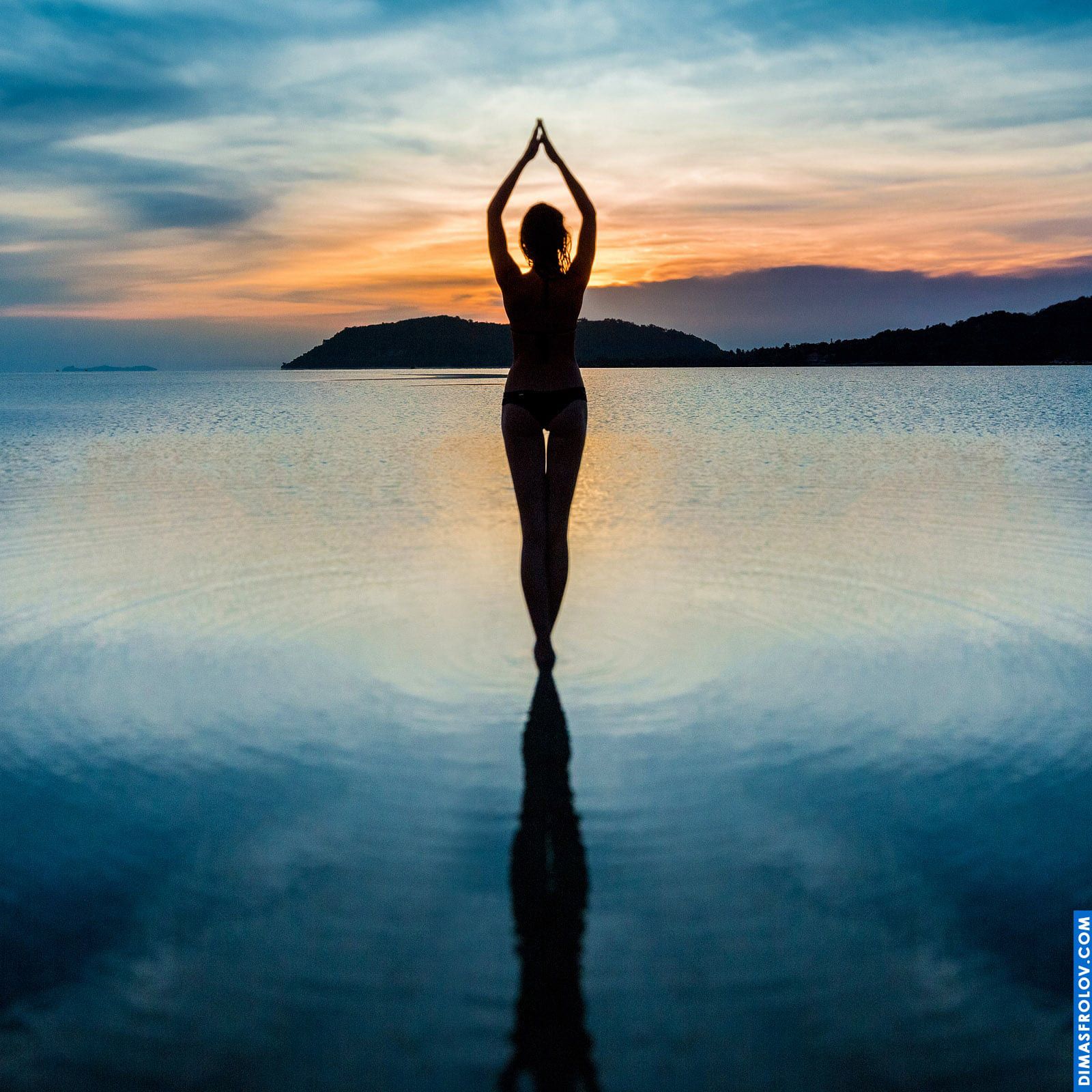 Silhueta de uma mulher em pé na água durante a meditação ao pôr do sol