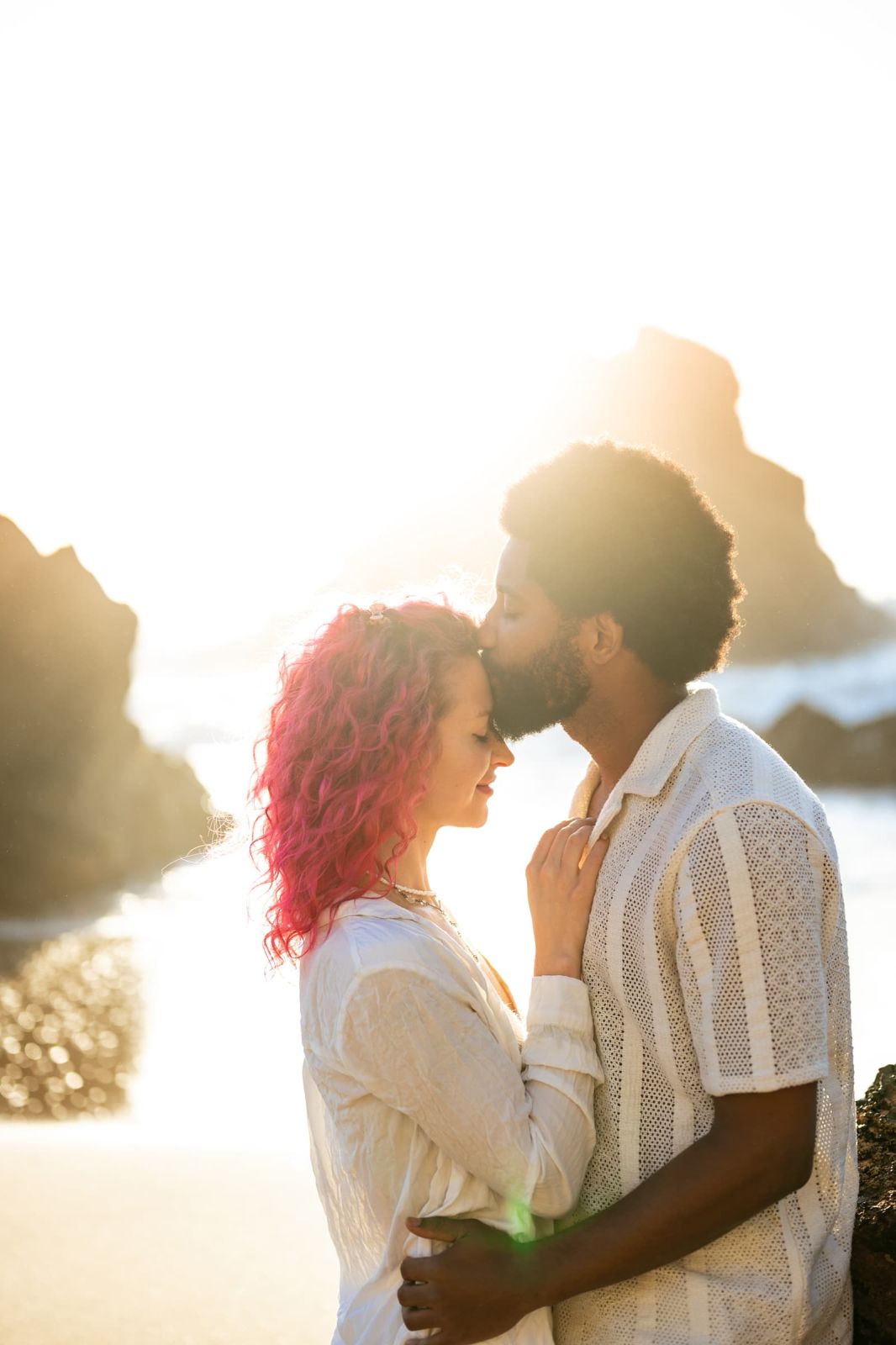 Forehead kiss on the beach in strong backlight from the setting sun