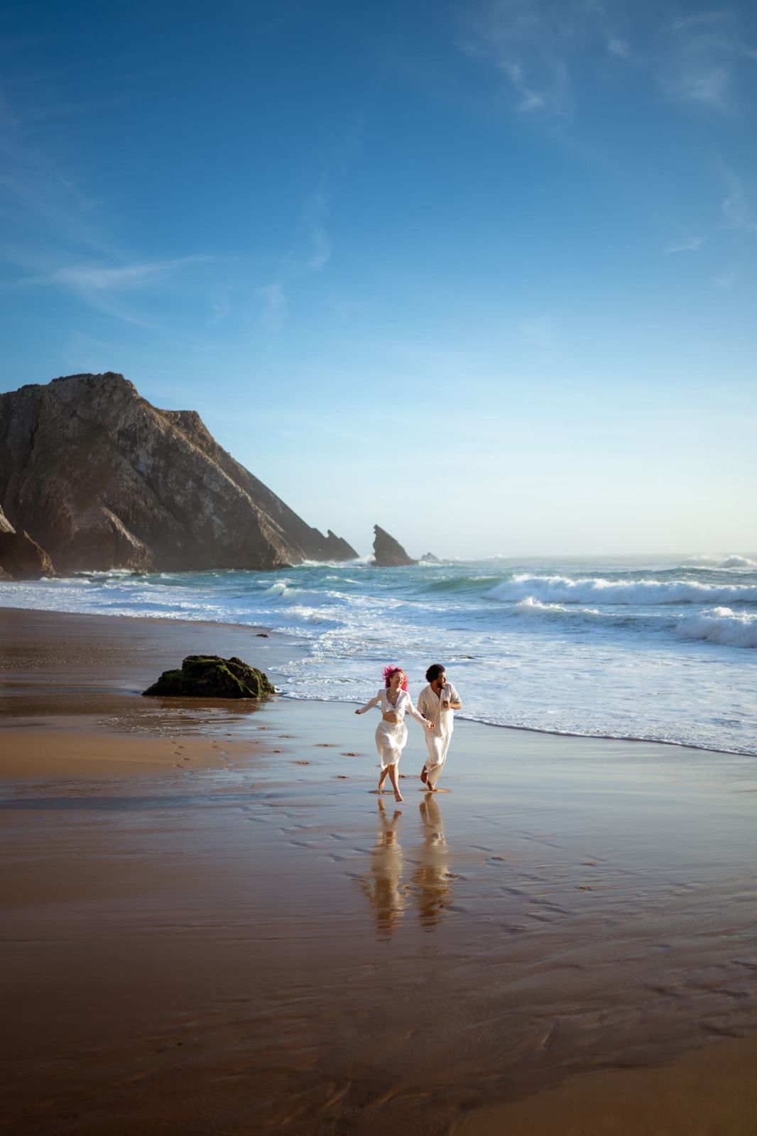 Couple running along the shoreline below the cliffs of a wide Atlantic beach