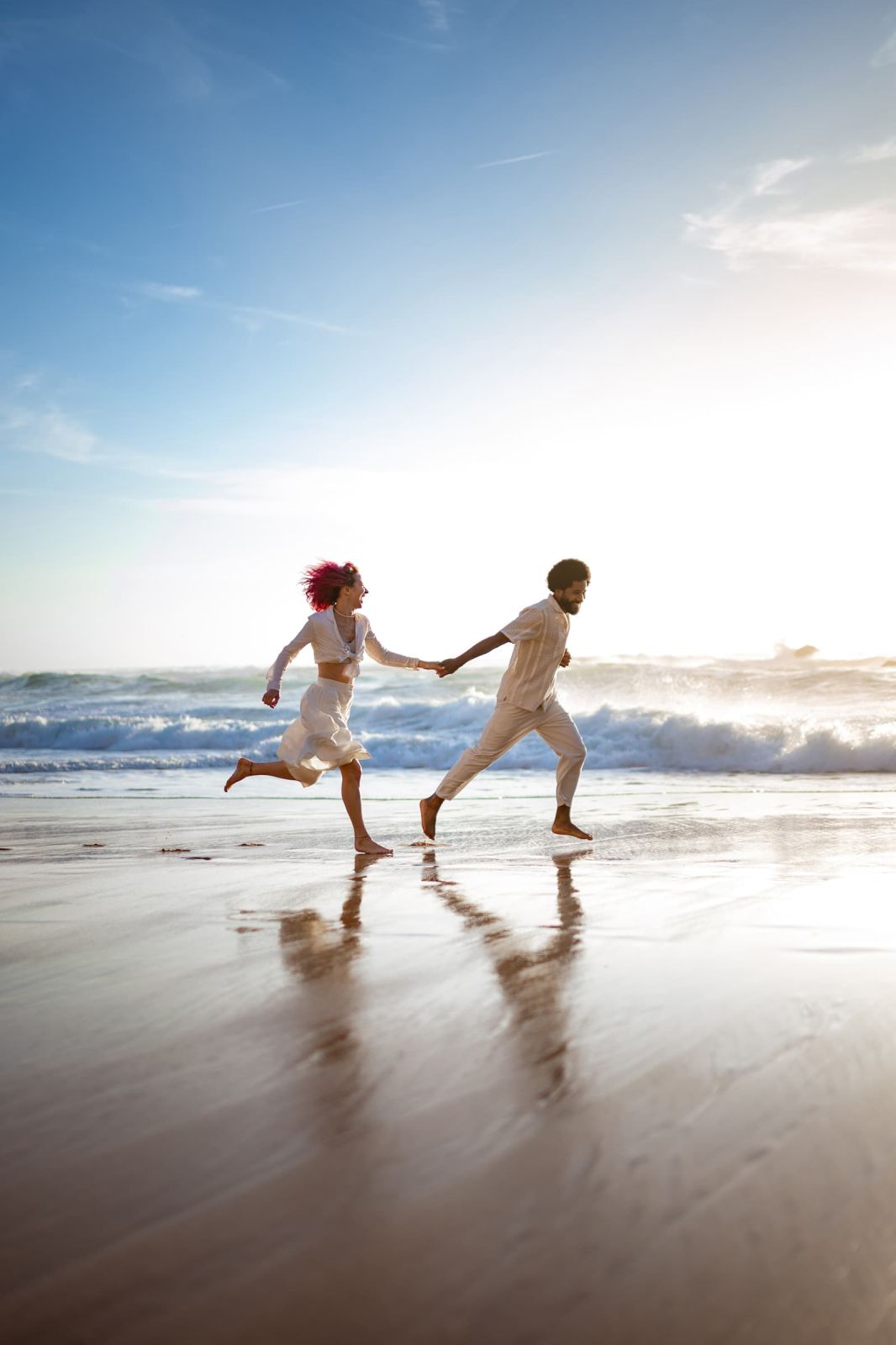 Couple running barefoot hand in hand along the wet sand