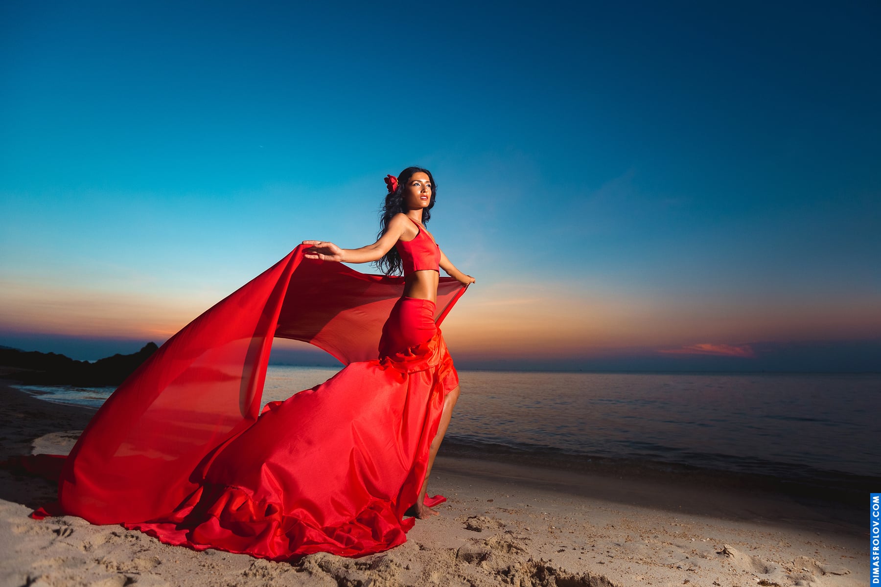 Powerful pose in a flowing red gown on the beach at sunset