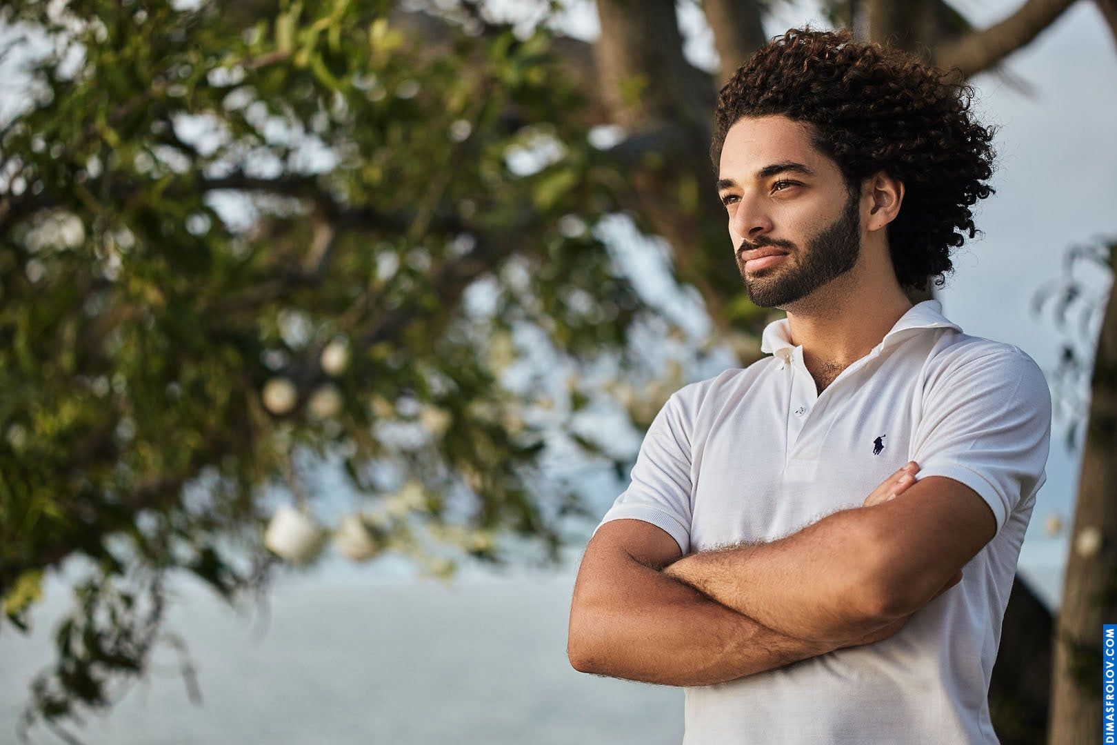 A casual seaside portrait: a man in a polo shirt stands by the water during a laid-back photo shoot