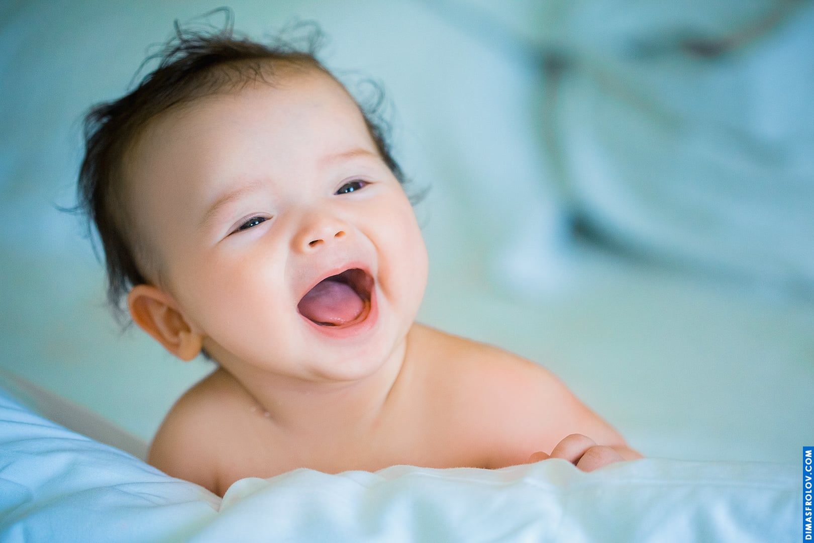 Joyful baby portrait — big open-mouthed smile and playful energy