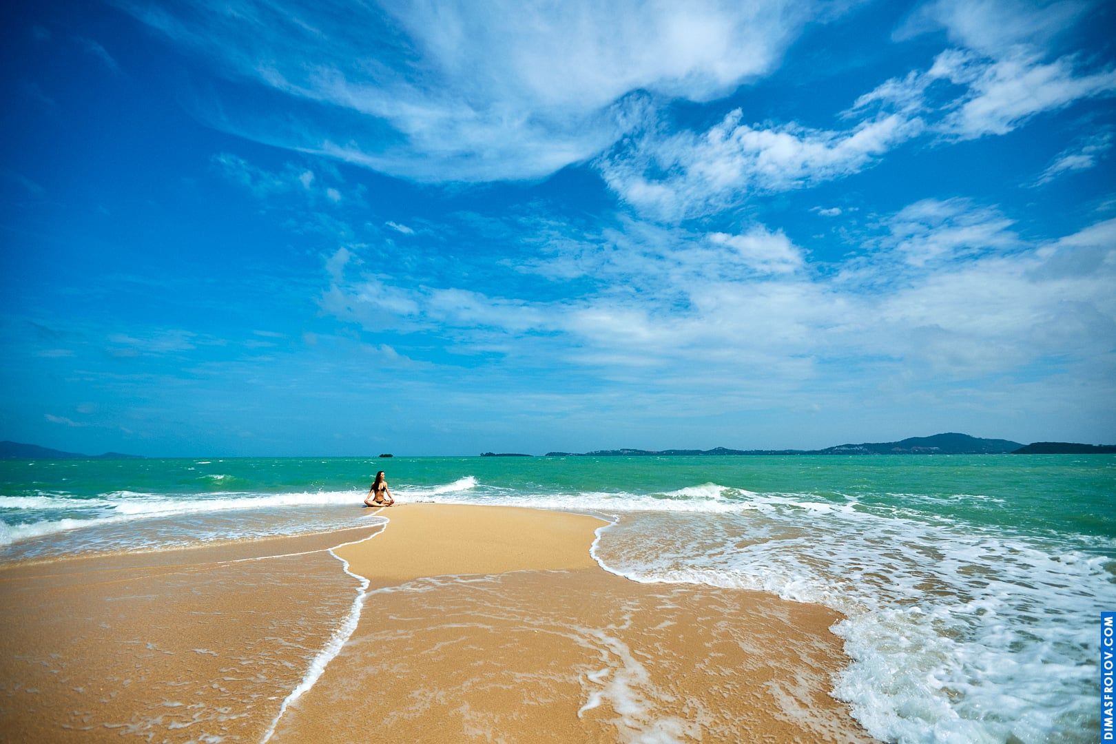 Paisagem de praia em grande angular com uma mulher caminhando em direção ao oceano