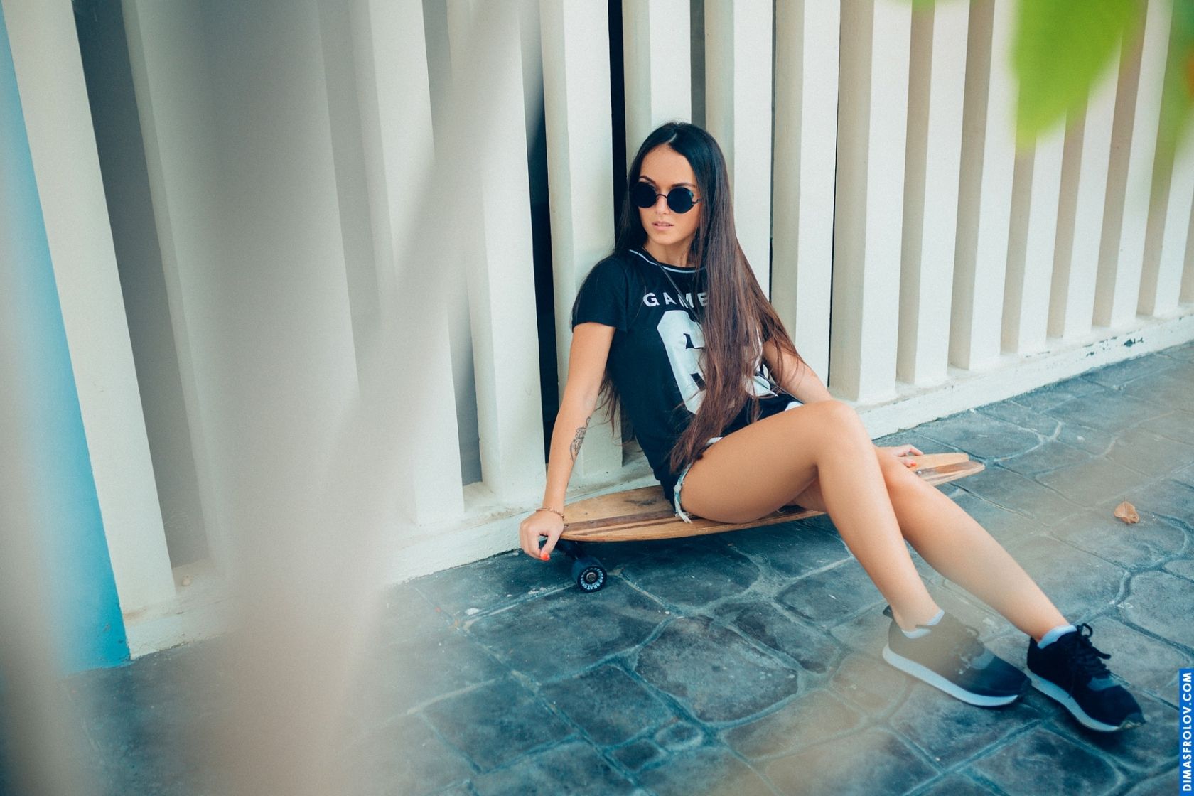 Urban fashion look with sunglasses and sneakers by the pool wall