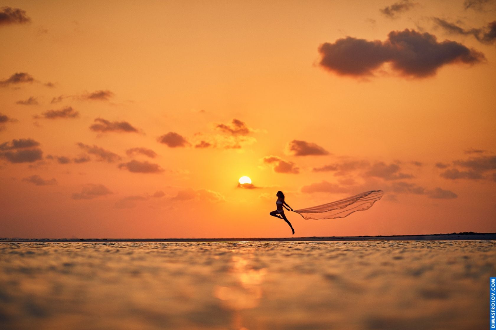 Silhouette of a girl jumping on the water at sunset during a creative photo session