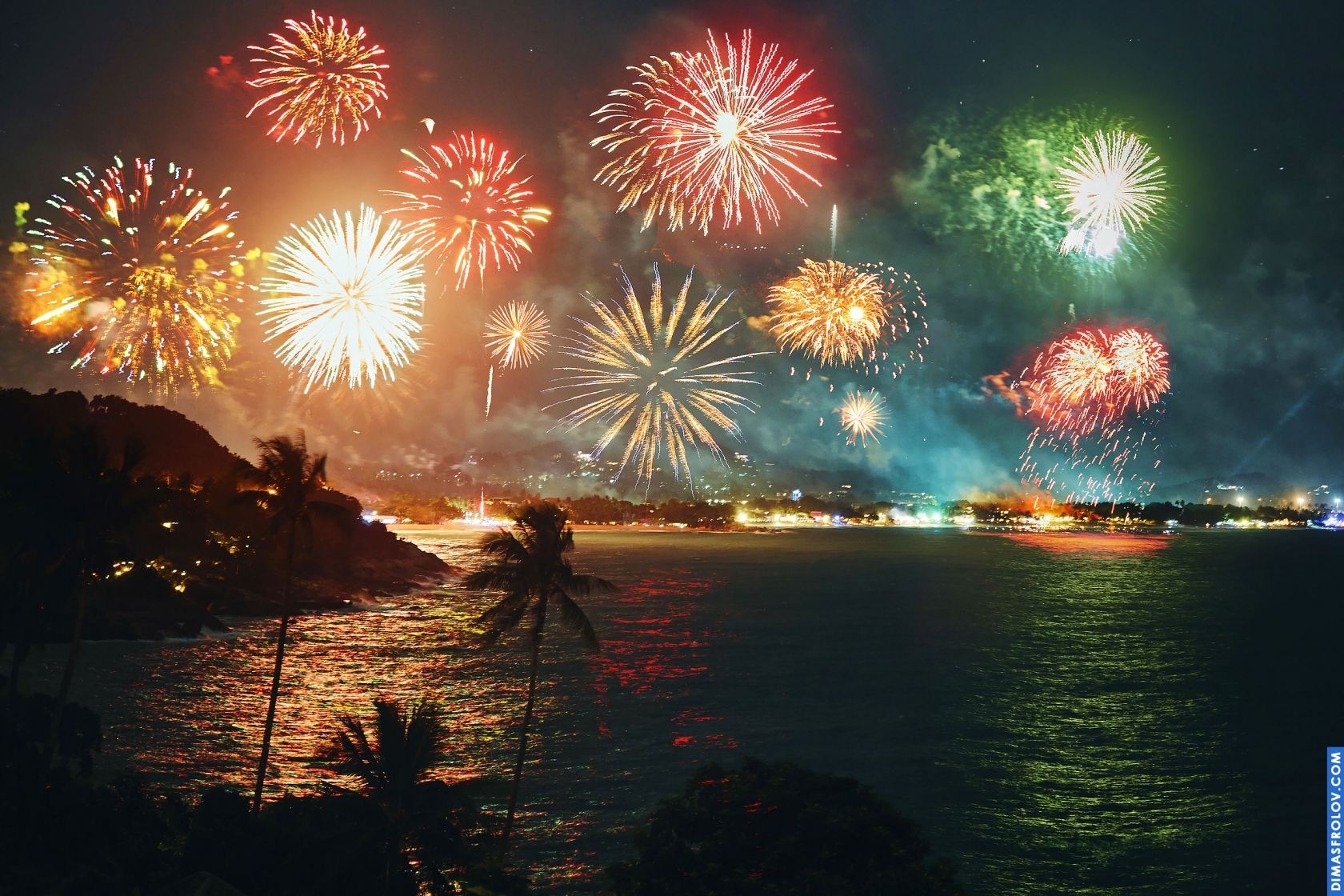 Um espetáculo de fogos de artifício sobre uma cidade escura à noite, iluminando o céu com cores vibrantes.