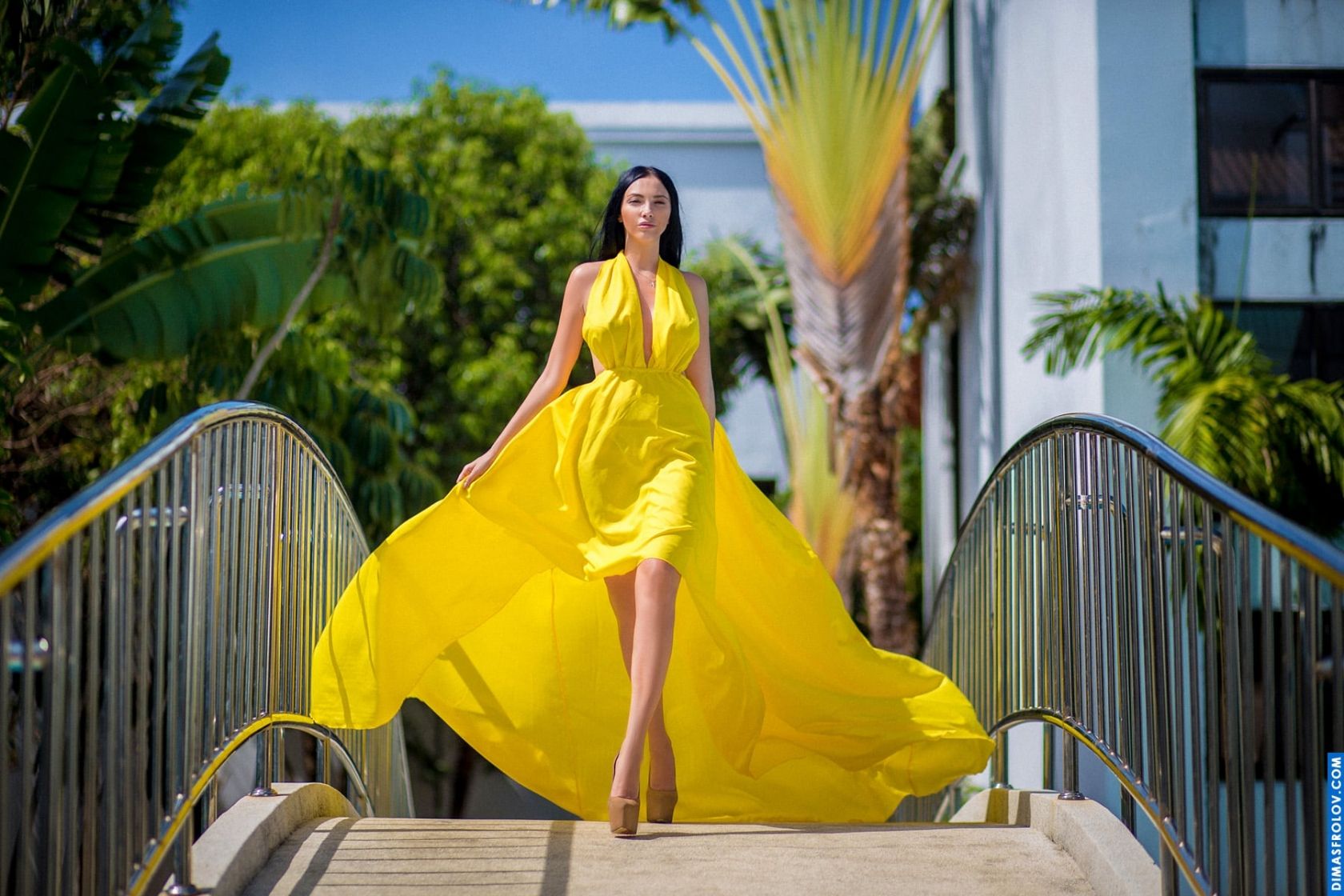 Elegant woman walking down tropical stairs in bright yellow dress