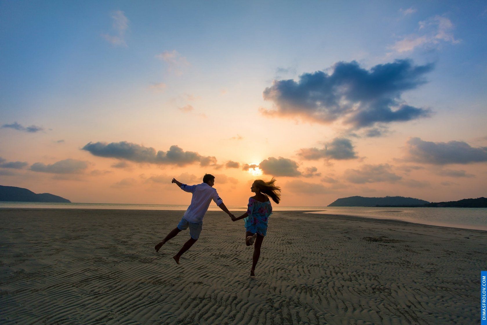 Running together barefoot along the wet sand during couple session