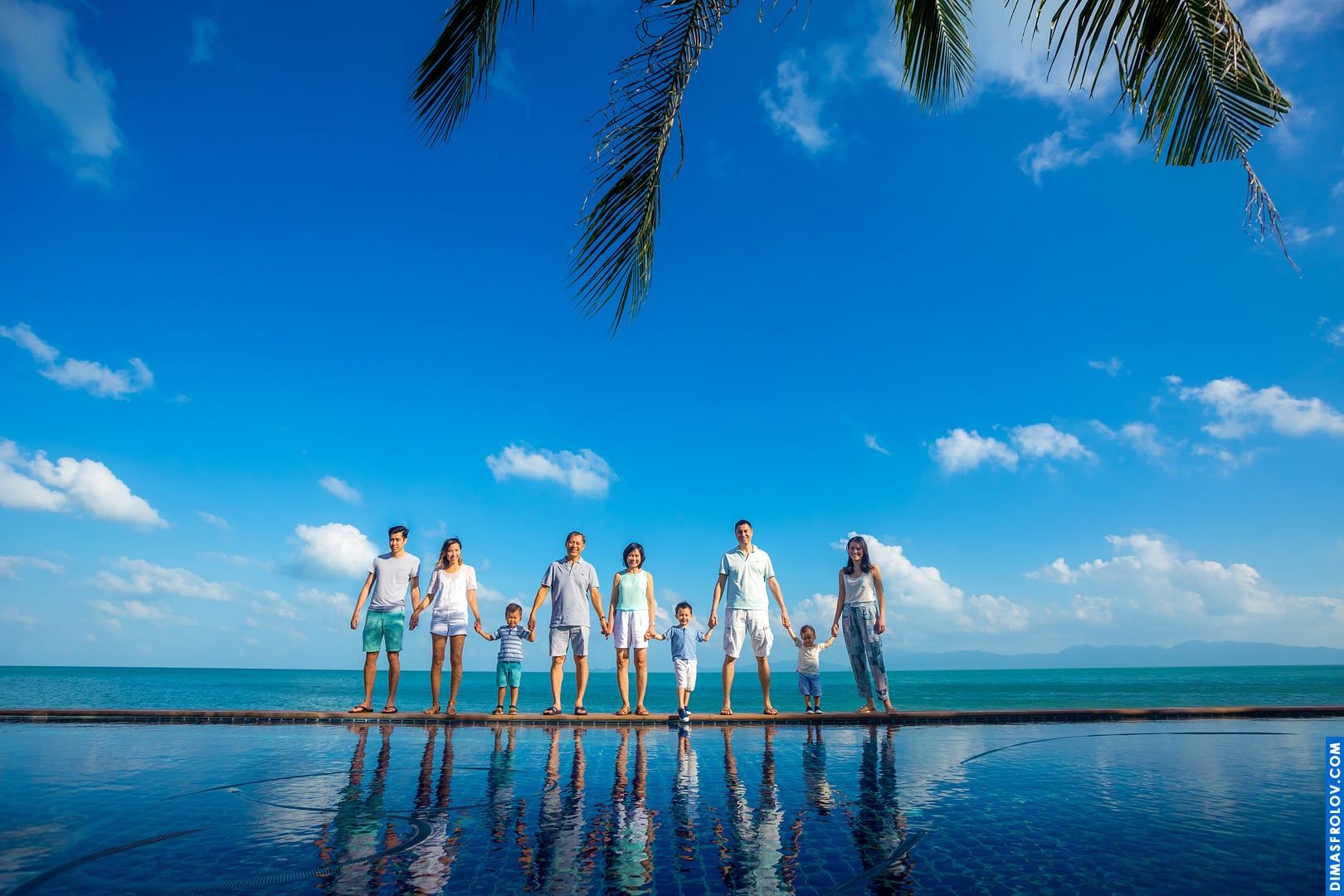 Family photo session in all white by the infinity pool — elegant and symmetrical portrait