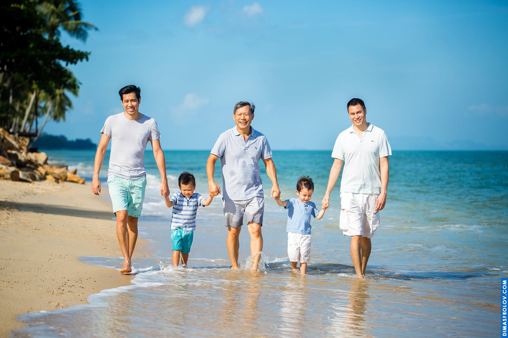 Three generations family photo shoot on the beach — two dads, grandpa and boys in a relaxed portrait