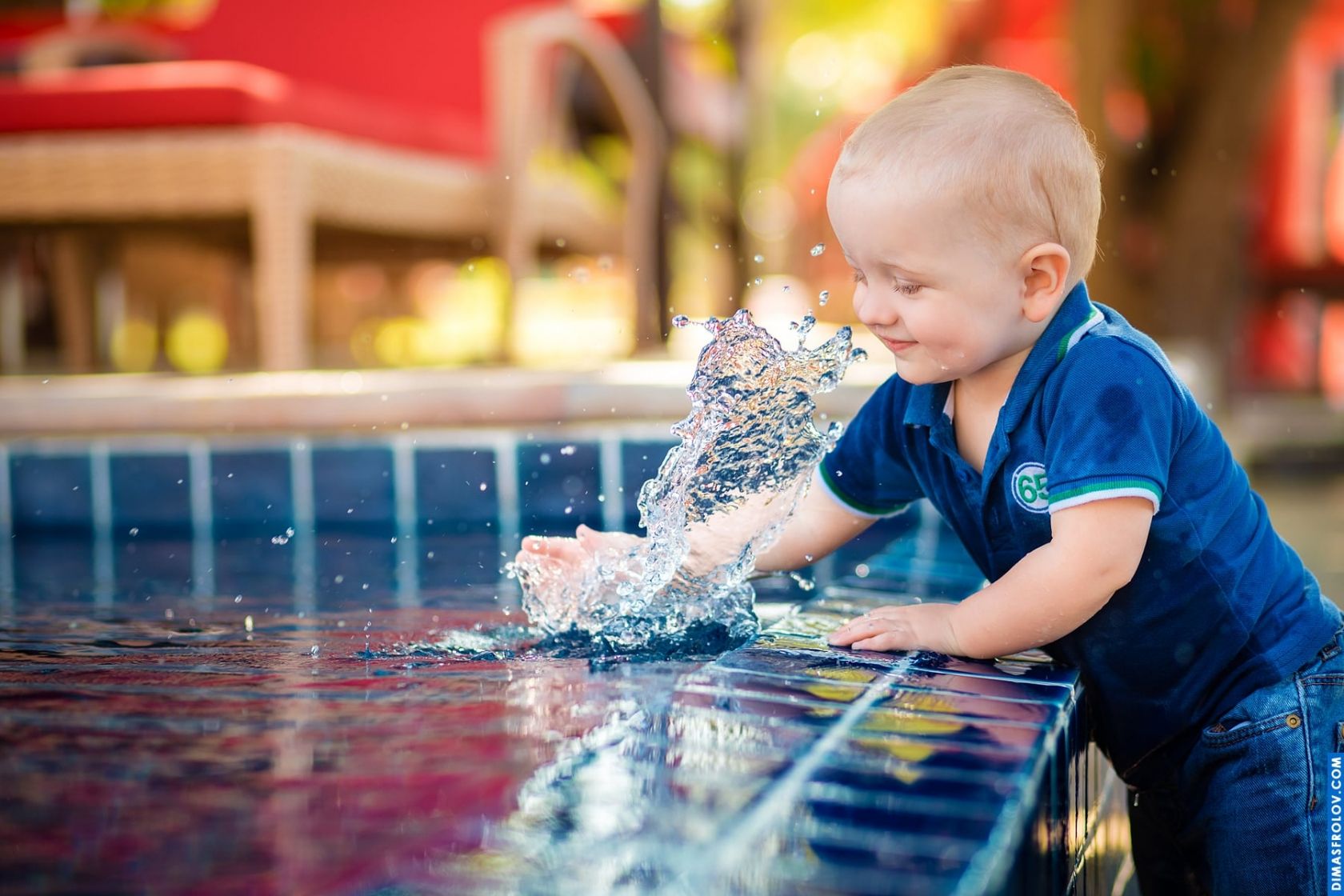 Candid kids photo — toddler splashing at the edge of the pool