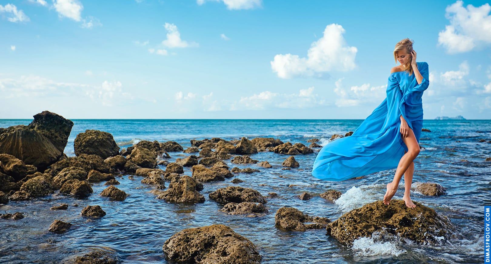 Delicate girl like a sea fairy in a flowing blue dress standing in water
