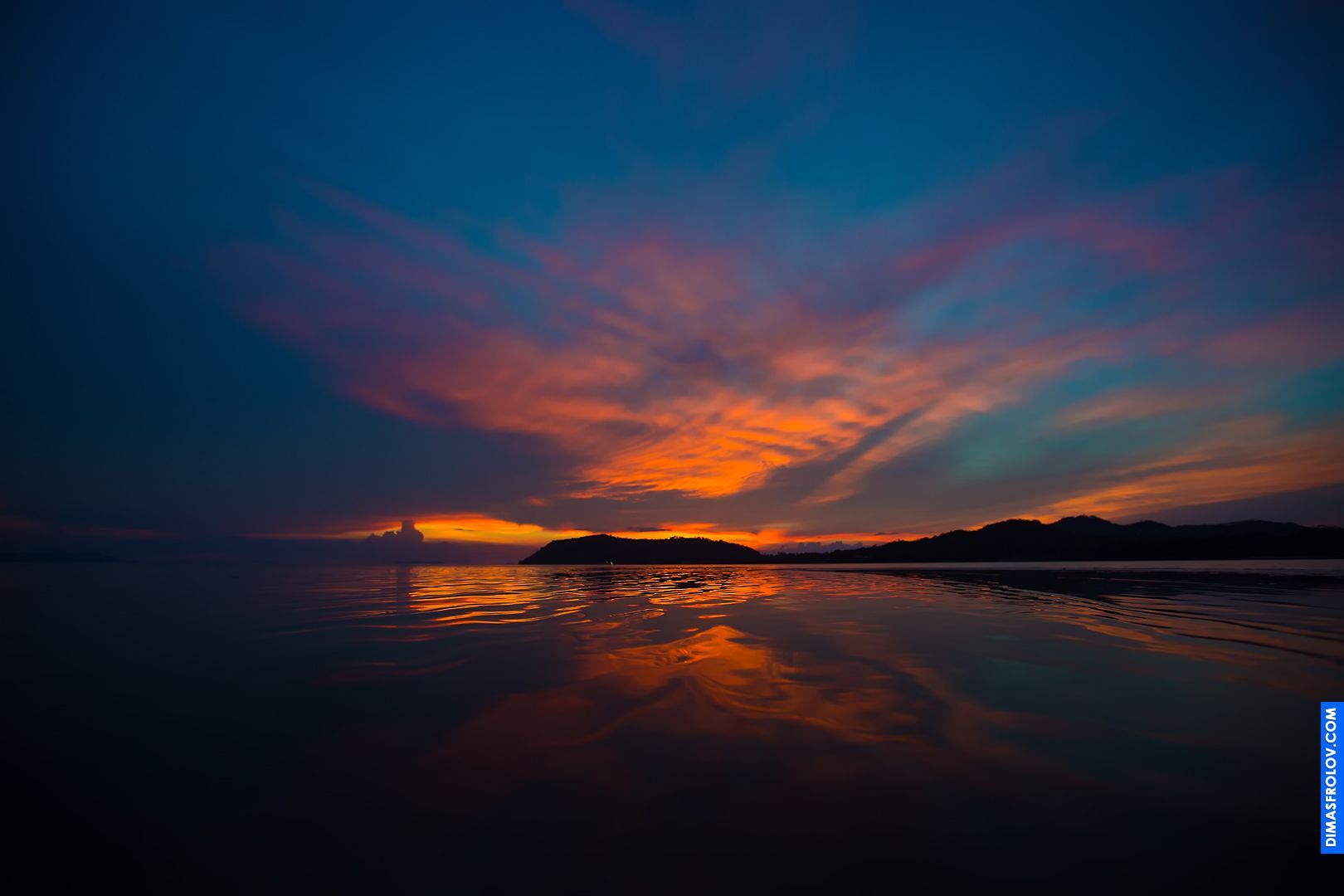 Pôr do sol vibrante sobre um oceano calmo com a silhueta de um pequeno barco no horizonte