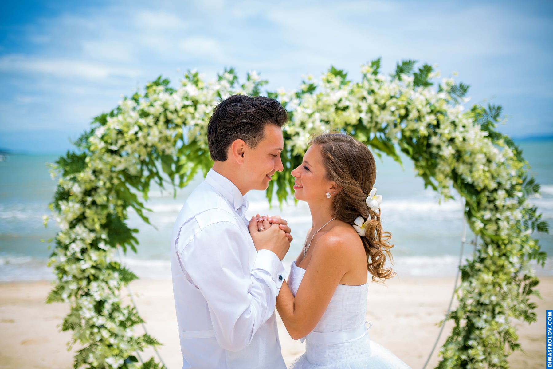 Молодята під квітковою аркою на пляжі — класика весільної фотосесії