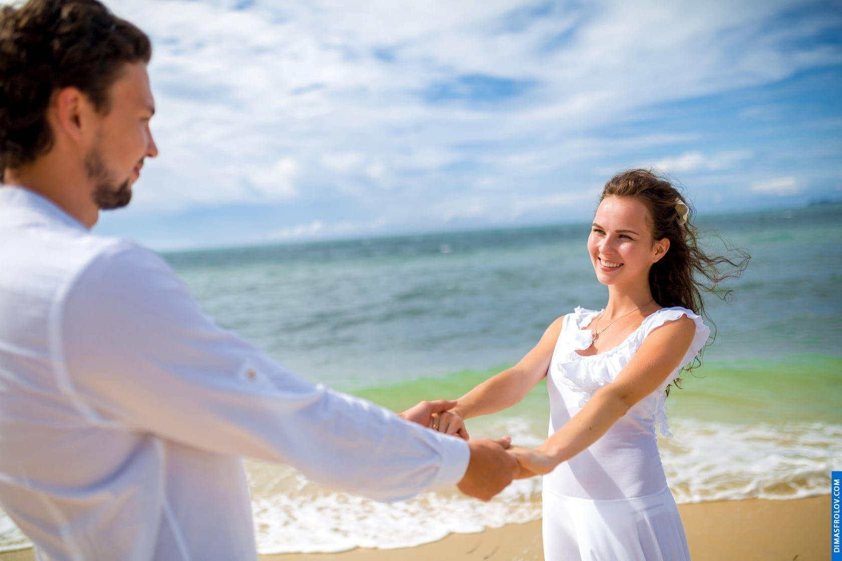 Romantic photo of couple holding hands by the sea