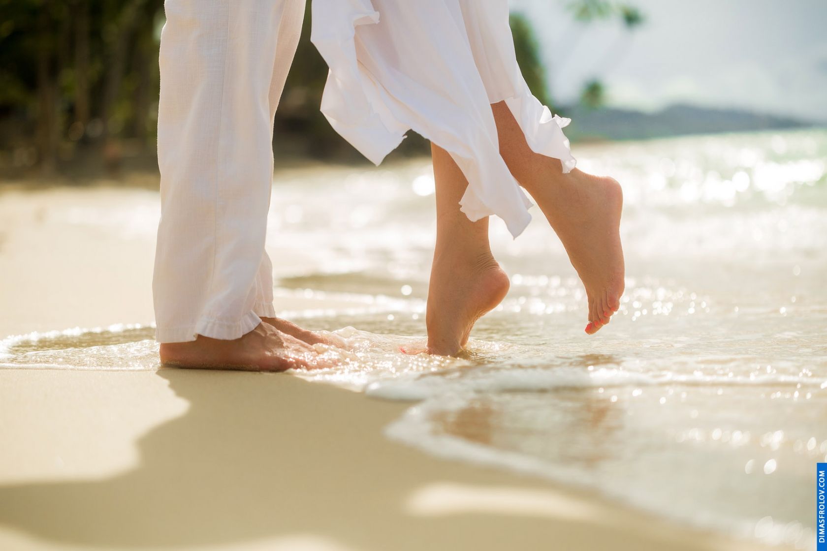 Close-up of couple’s feet walking along the shoreline