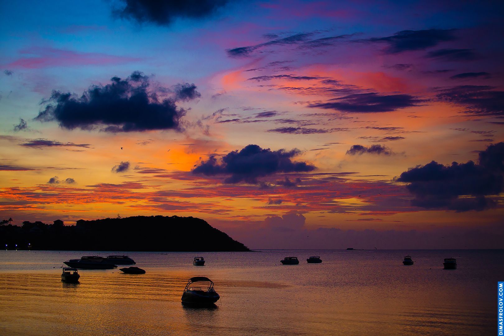 Pôr do sol vibrante sobre o oceano com nuvens coloridas e uma superfície da água calma e reflexiva