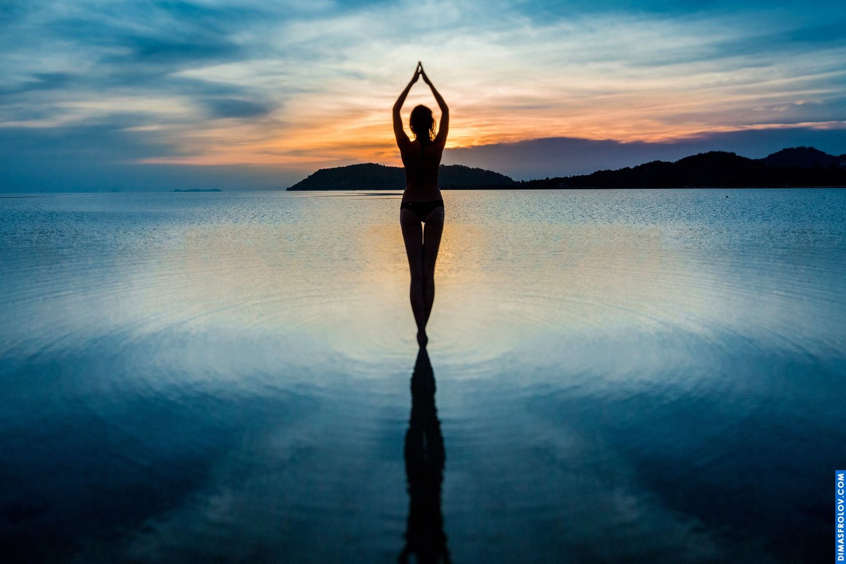 Silhueta artística de uma mulher fazendo pose de yoga na água ao amanhecer