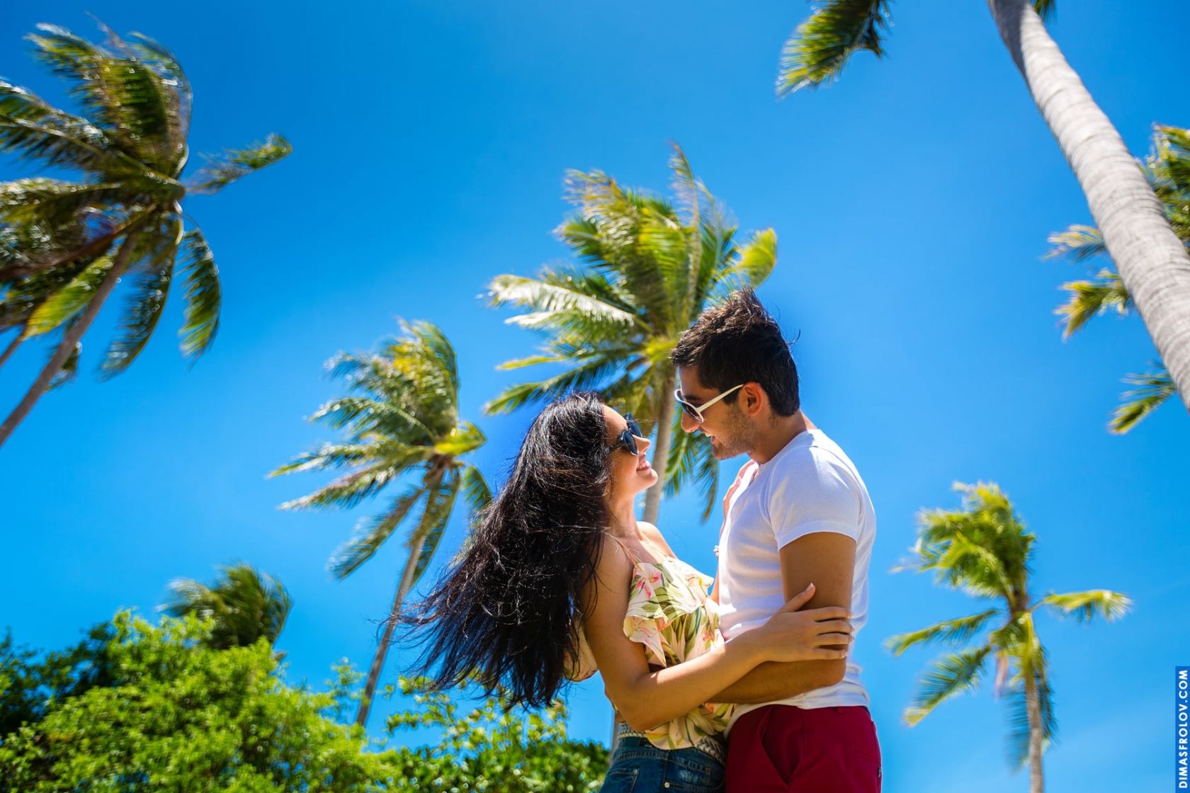 Couple photo with palms and blue sky in tropical paradise
