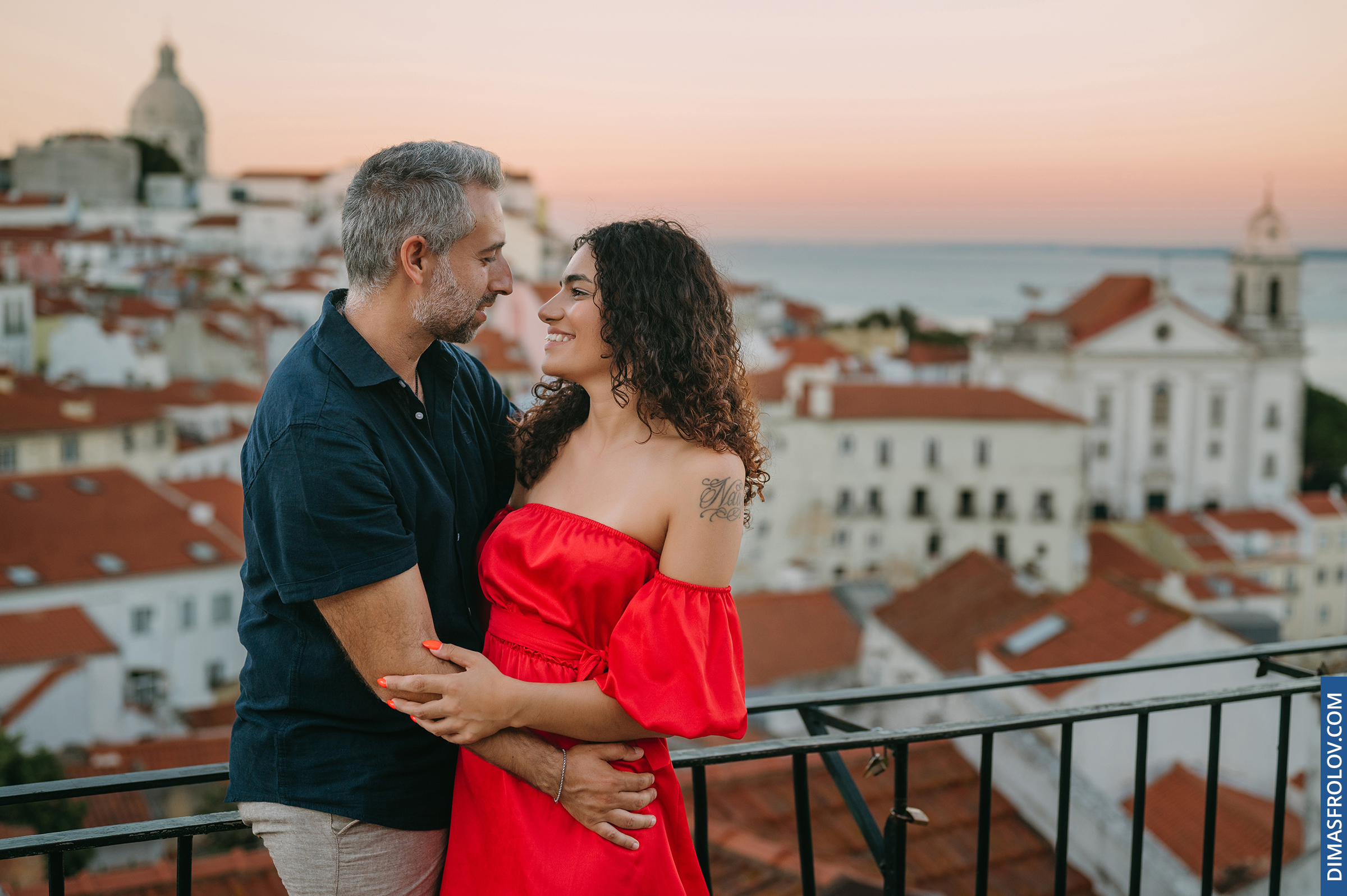Couple embracing on rooftop terrace at sunset in Lisbon