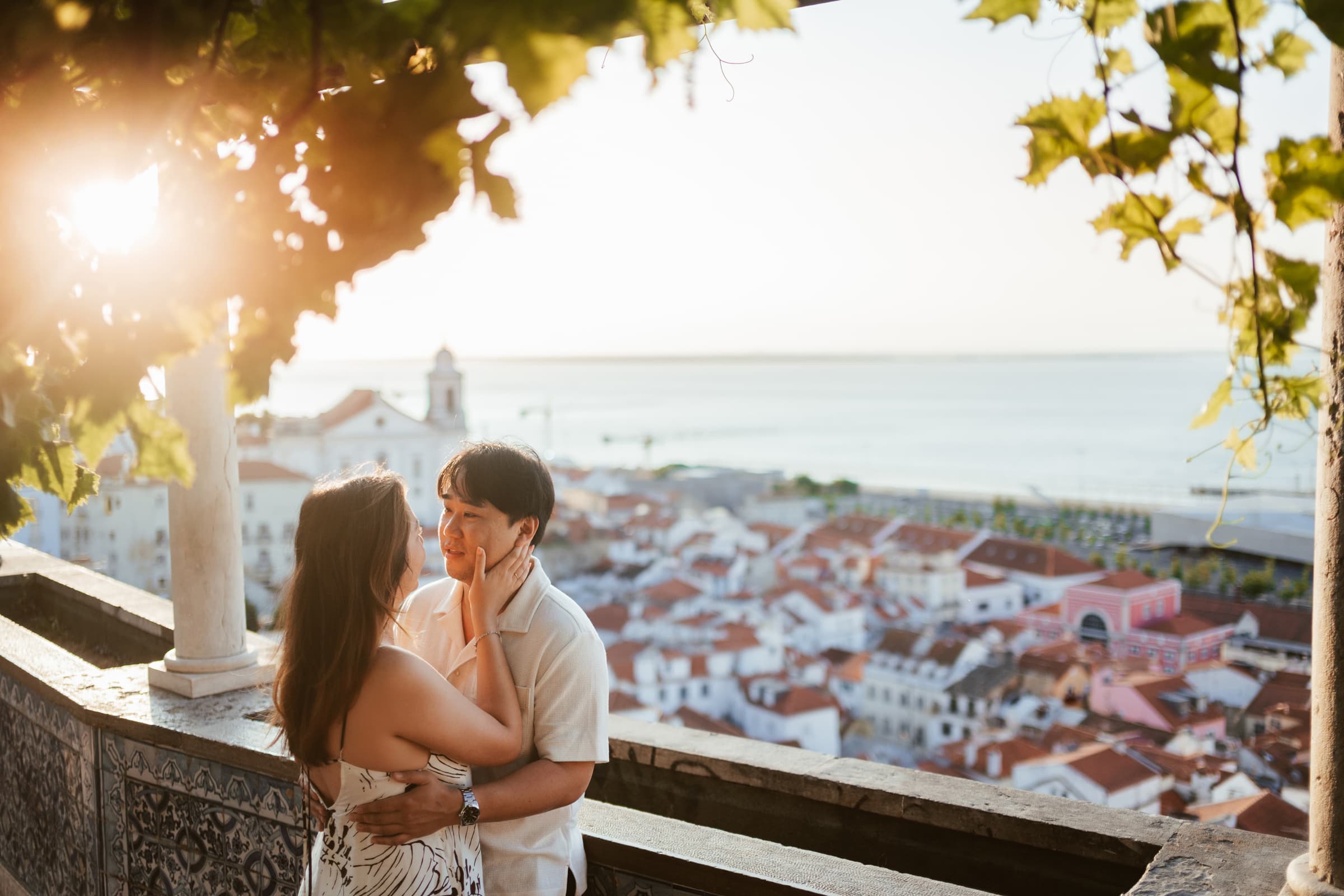 Couple embracing at a tiled Lisbon viewpoint above the Alfama rooftops
