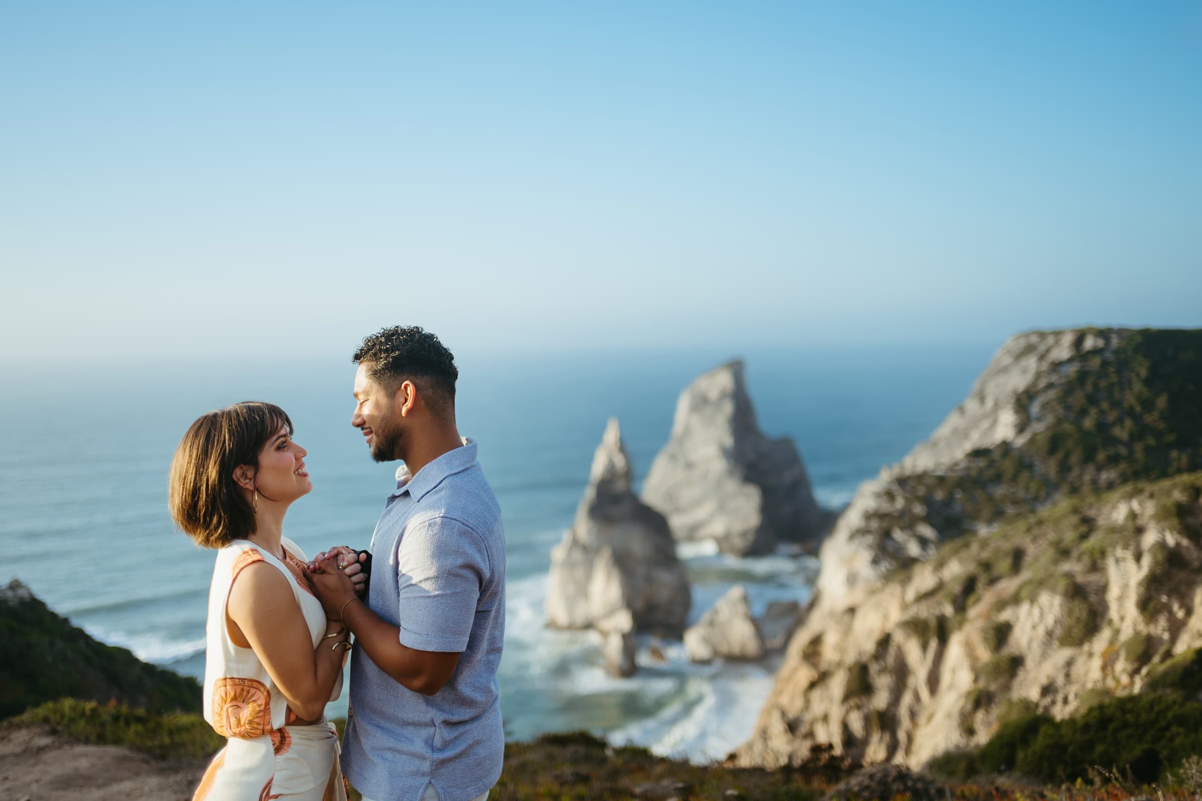 Couple holding hands on a clifftop above the Atlantic rocks of the Sintra coast