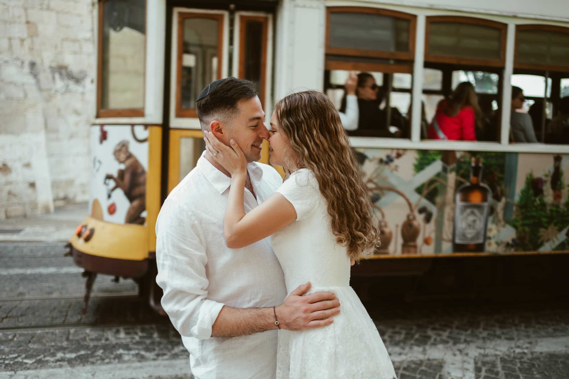 Couple about to kiss in front of a vintage yellow Lisbon tram