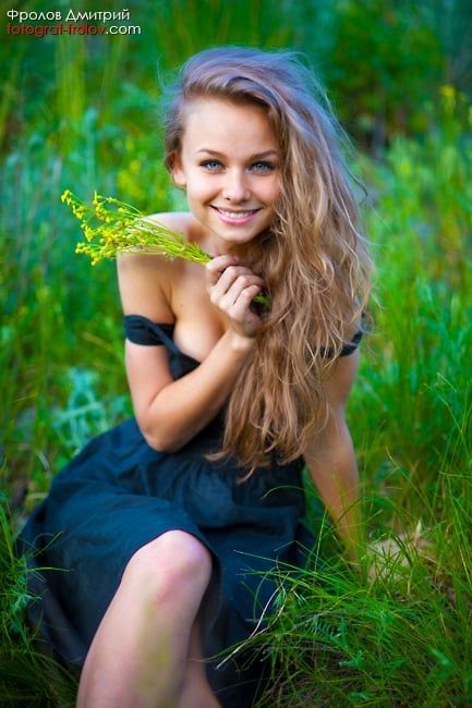 Outdoor portrait of a cheerful girl holding wildflowers in a nature photo session