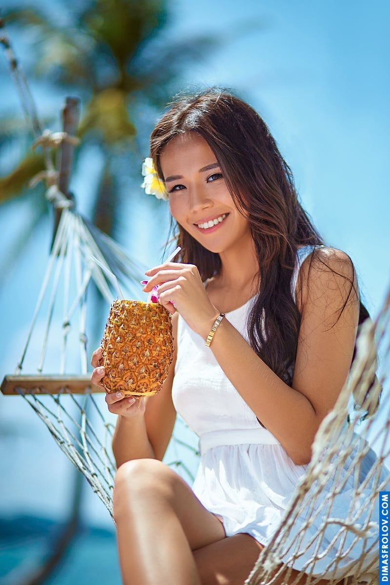 Retrato tropical de uma jovem alegre desfrutando de abacaxi em uma rede