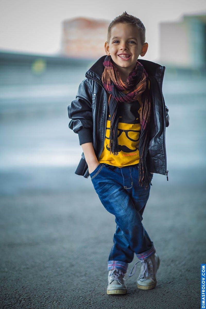 Stylish kids portrait — smiling boy in scarf and leather jacket posing confidently