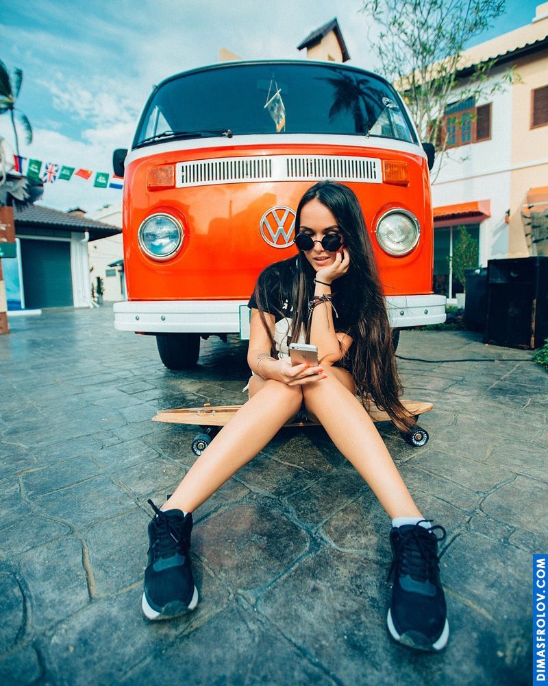 Cool girl in sunglasses relaxing by an orange vintage van with urban flair