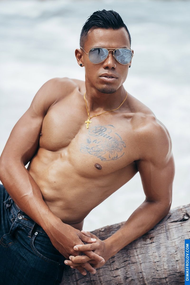 A striking seaside photo set: a tattooed man poses confidently by the ocean during a bold photo session
