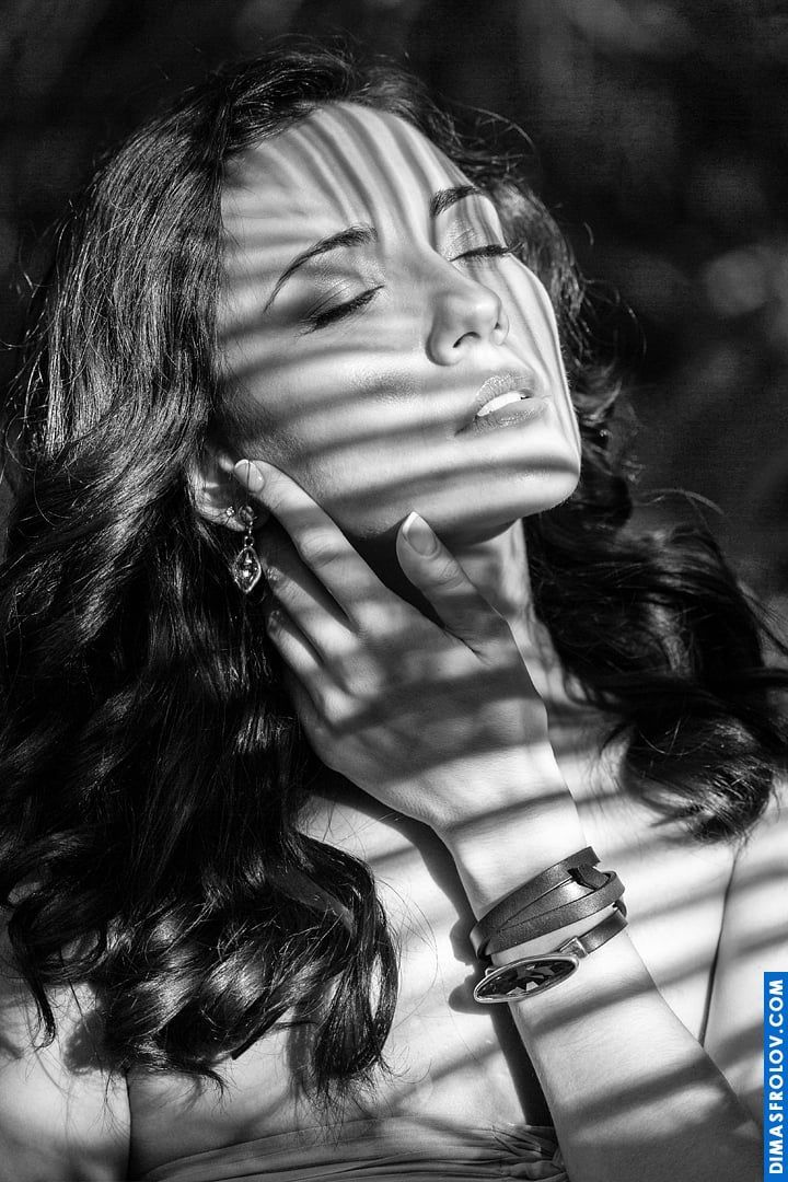 Black and white artistic portrait with light-shadow pattern on woman’s face