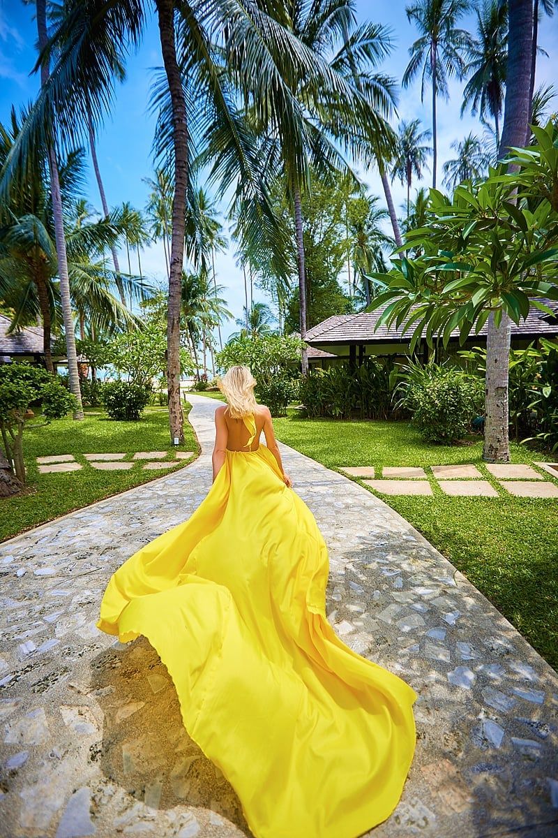 Fashion-style back view of a blonde walking in a long yellow gown