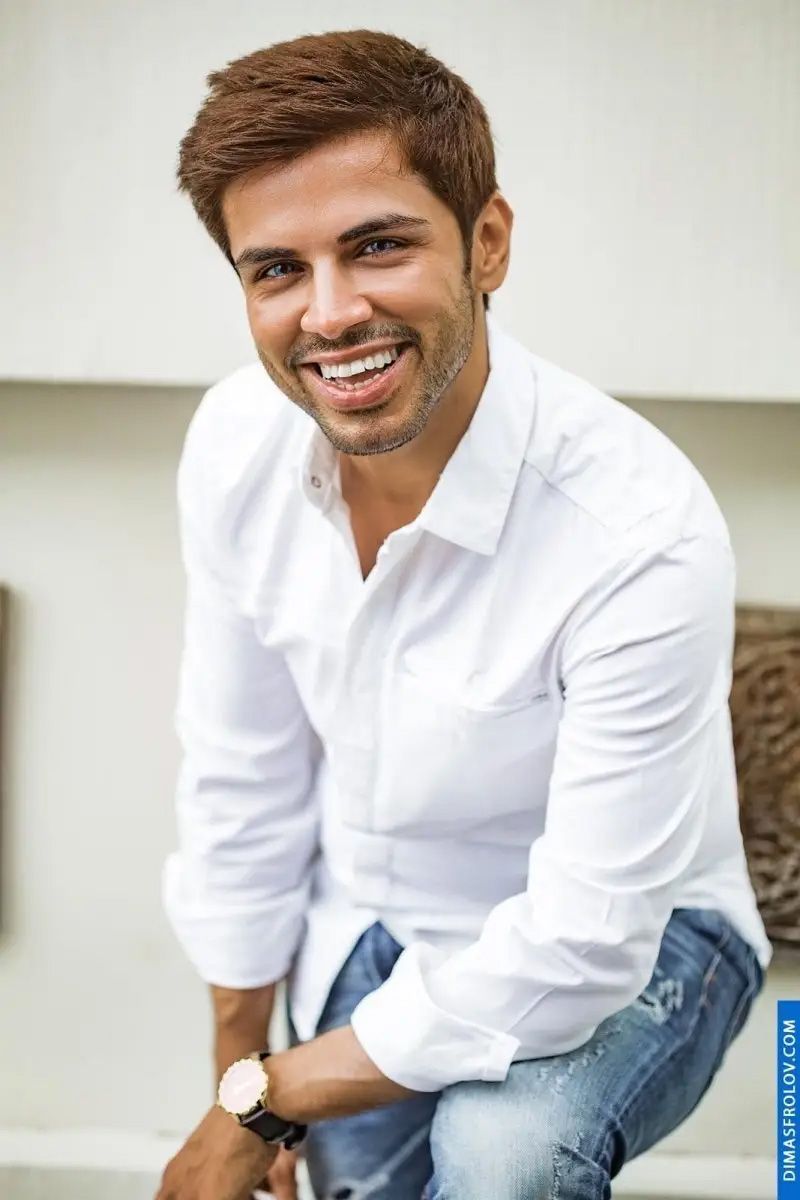 Bright male portrait of smiling man in white shirt and jeans in daylight
