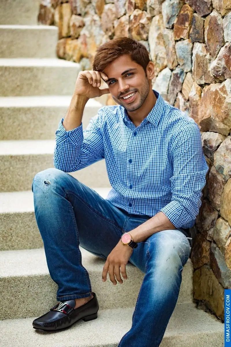 Outdoor portrait of smiling man in blue checked shirt on stone stairs