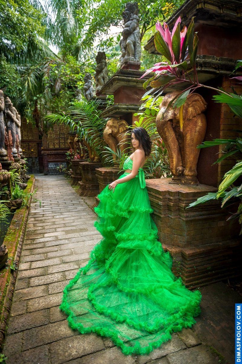 Elegant woman in a bright green gown walking through an exotic temple garden